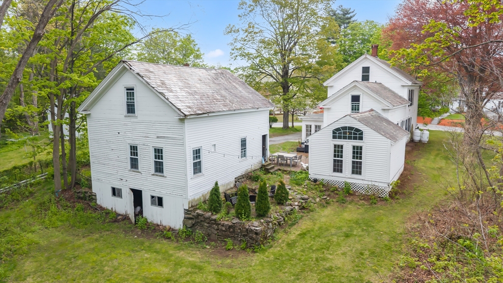 10 Maple Street Sturbridge, MA 01566 - Photo 37 of 40 a view of a white house with large windows and a yard with plants and large trees