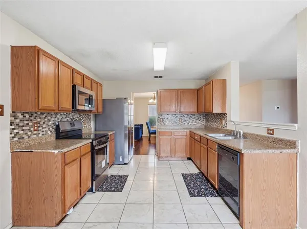 a large kitchen with stainless steel appliances granite countertop a stove top oven a sink dishwasher and cabinets
