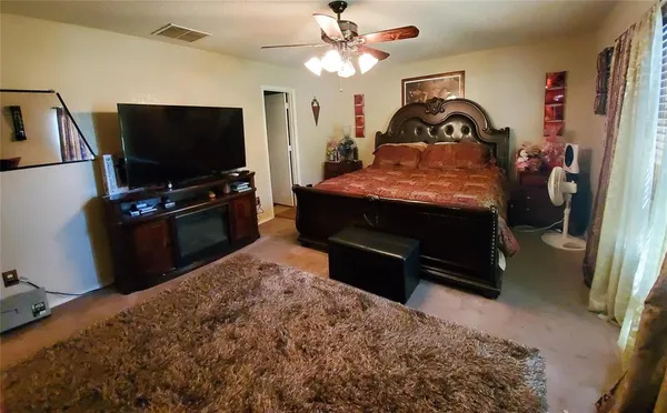 a bedroom with a bed and a flat tv screen on dresser