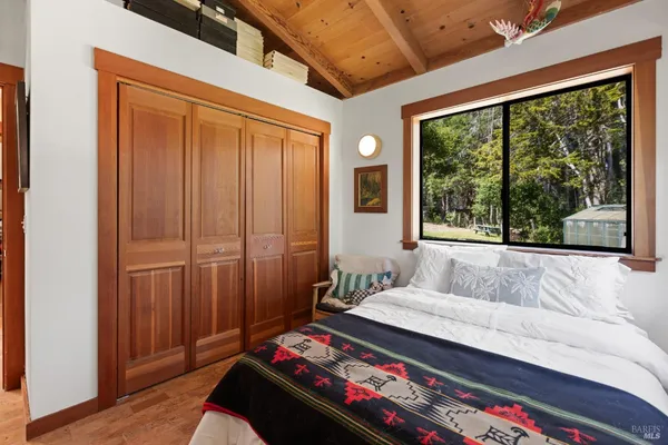 a bedroom with a bed and a large window with wooden floor