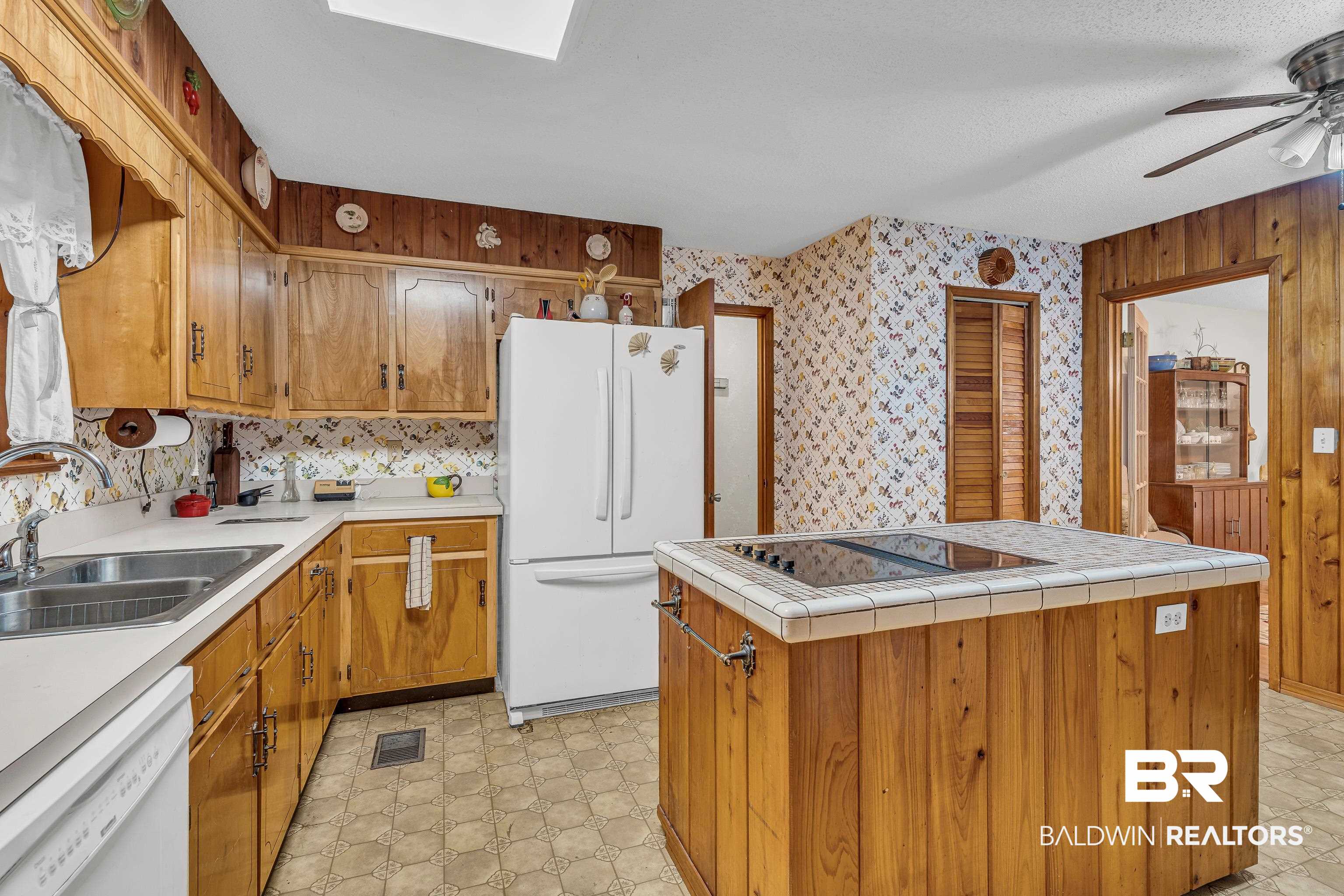 72075 Highway 59 Little River, AL 36550 - Photo 11 of 40 Kitchen featuring white appliances, brown cabinets, a skylight, a kitchen island, and tile counters