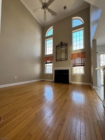 an empty room with wooden floor fan and windows