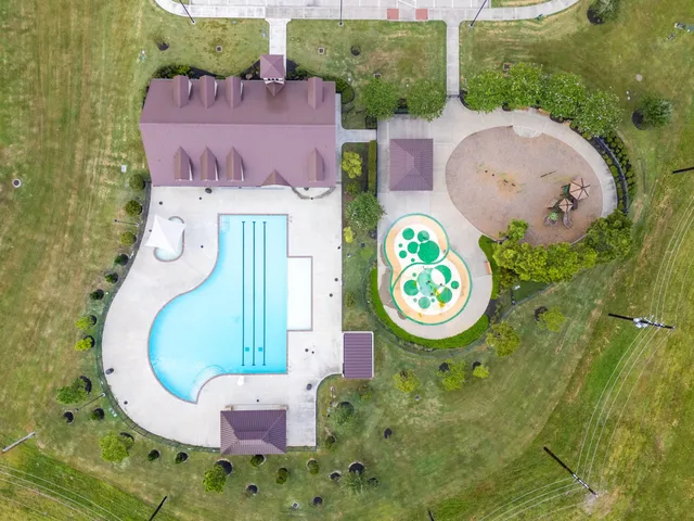 an aerial view of a swimming pool with outdoor seating and yard