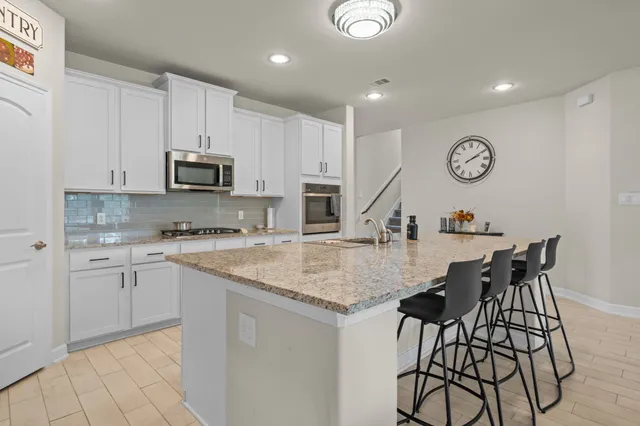 a kitchen with stainless steel appliances granite countertop a stove top oven a sink a dining table and chairs