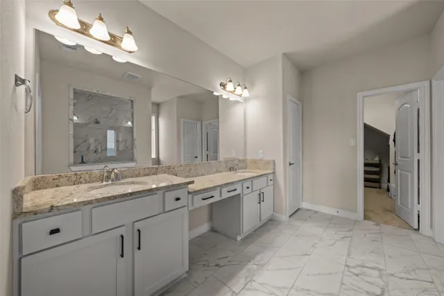 a bathroom with a granite countertop double vanity sink a mirror and shower