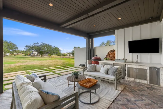 a living room with furniture a flat screen tv and a floor to ceiling window next to a yard
