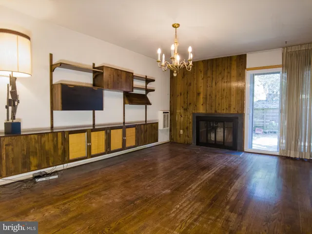 a view of a room with wooden floor fireplace and windows