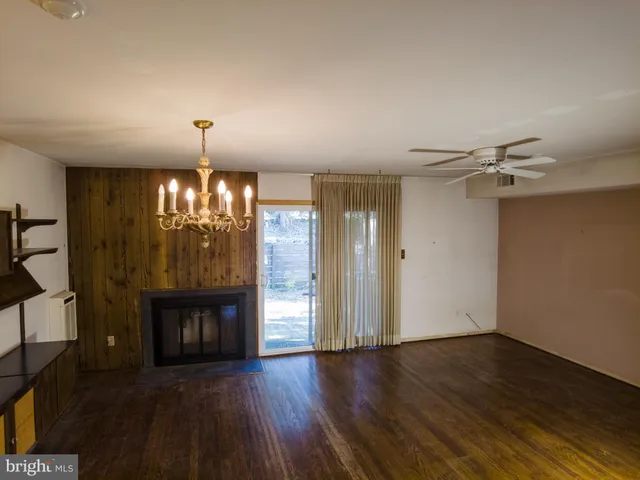 a view of an empty room with wooden floor fireplace and a window