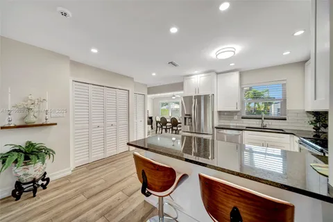 a kitchen with granite countertop a table chairs stove a refrigerator and cabinets
