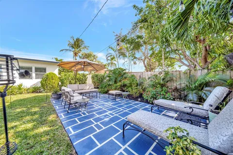 a view of a backyard with table and chairs potted plants and large tree