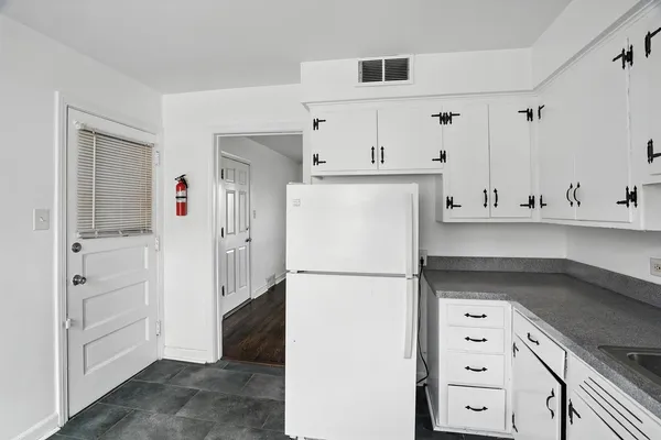 a kitchen with stainless steel appliances granite countertop white cabinets sink and a refrigerator