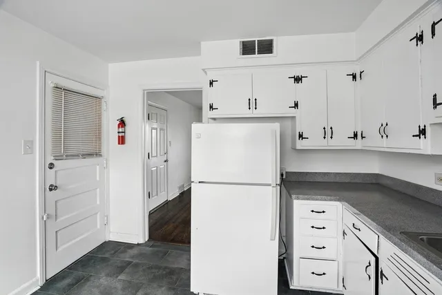 a kitchen with stainless steel appliances granite countertop white cabinets sink and a refrigerator