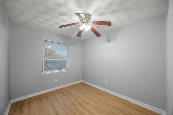 an empty room with windows and fan