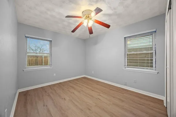 a view of an empty room with window and wooden floor