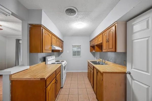a utility room with stainless steel appliances a stove a sink and a refrigerator