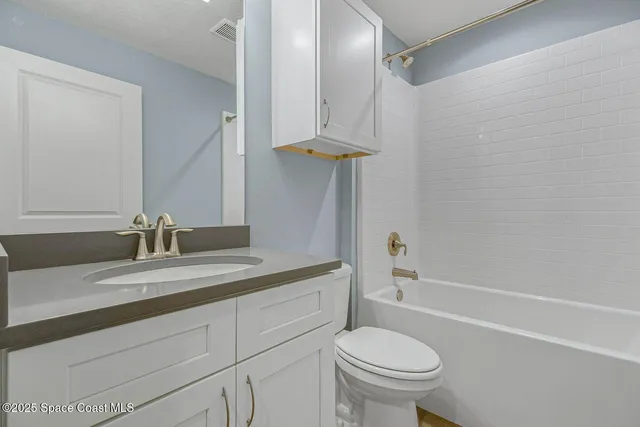 a bathroom with a granite countertop sink a toilet and a bathtub