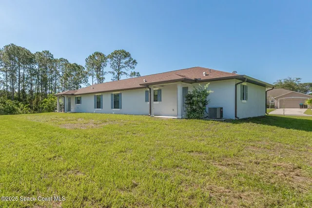 a front view of house with yard and trees in the background