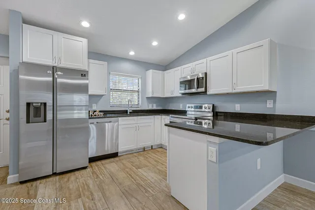a view of an empty room and kitchen view