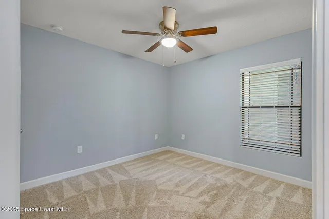 a view of an empty room with window and a chandelier fan
