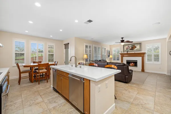 a large living room with stainless steel appliances granite countertop furniture a fireplace a flat screen tv and a refrigerator