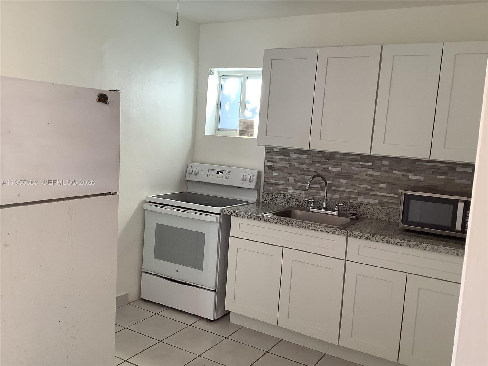 3620 Southwest 13th Terrace, Unit 3 Miami, FL 33145 - Photo 3 of 8 a kitchen with white cabinets and white appliances