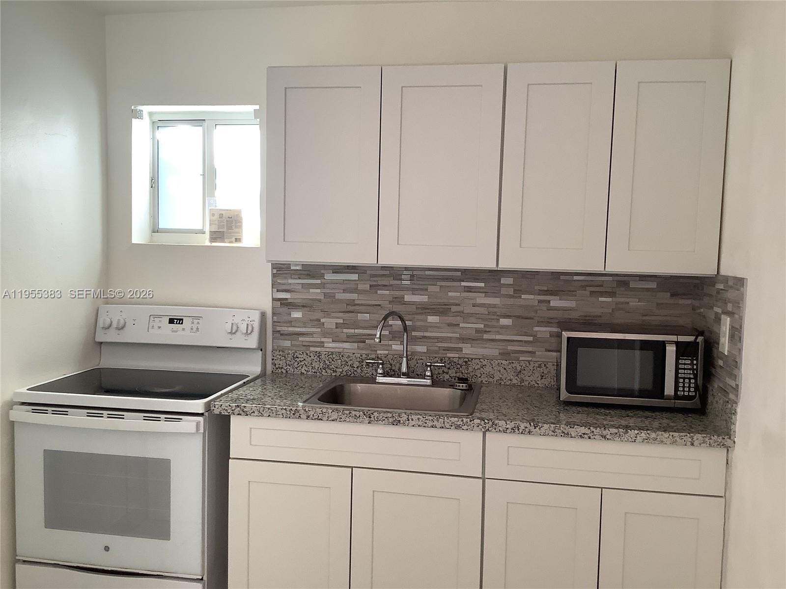 3620 Southwest 13th Terrace, Unit 3 Miami, FL 33145 - Photo 5 of 8 a kitchen with stainless steel appliances granite countertop white cabinets and a stove