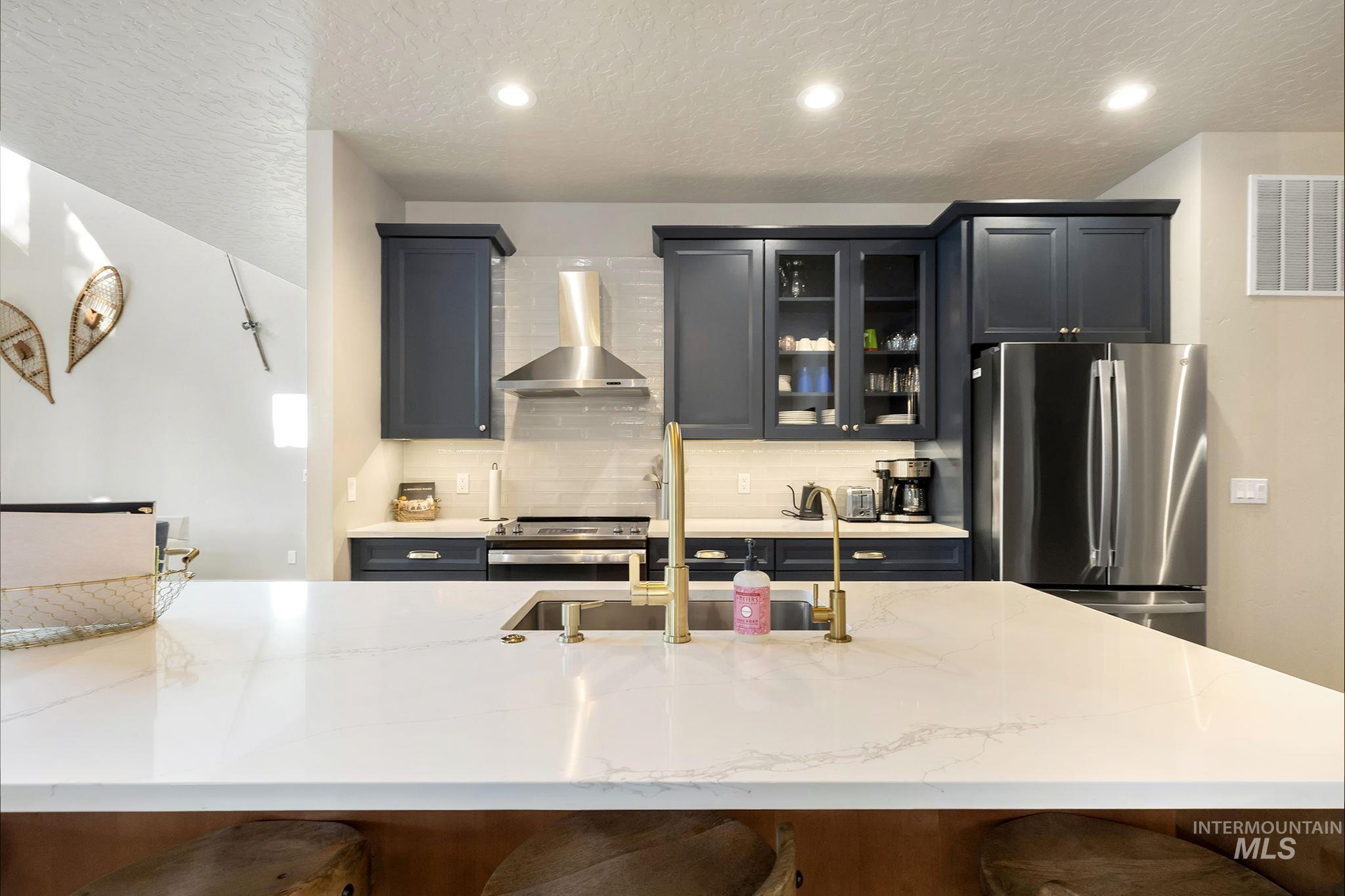 127 Jacks Loop Donnelly, ID 83615 - Photo 15 of 46 Kitchen with glass fronted cabinets, stainless steel appliances, light stone countertops, decorative backsplash, and a breakfast bar area
