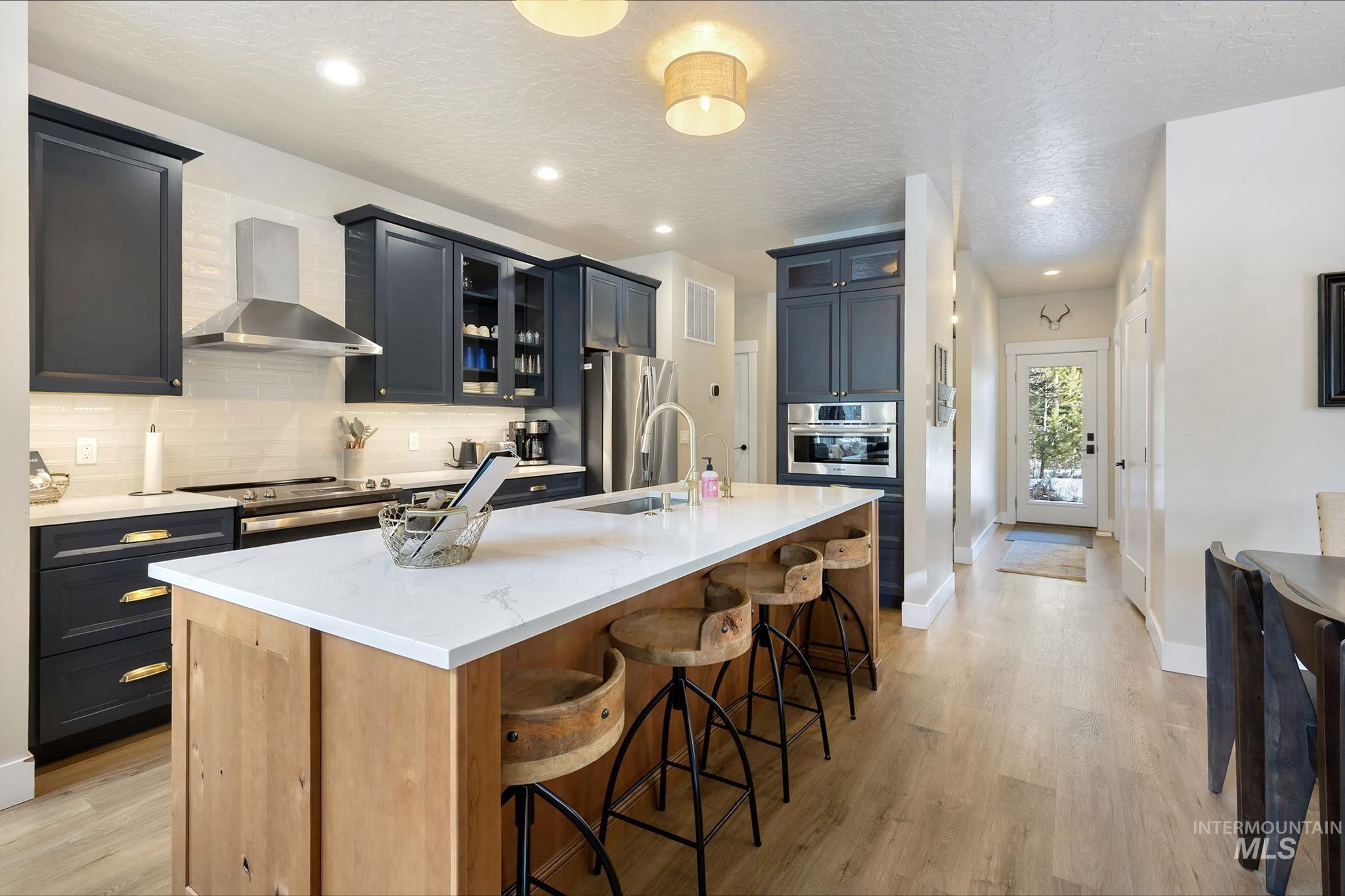 127 Jacks Loop Donnelly, ID 83615 - Photo 17 of 46 Kitchen with glass insert cabinets, light stone countertops, a large island with sink, a kitchen breakfast bar, and light wood-style flooring