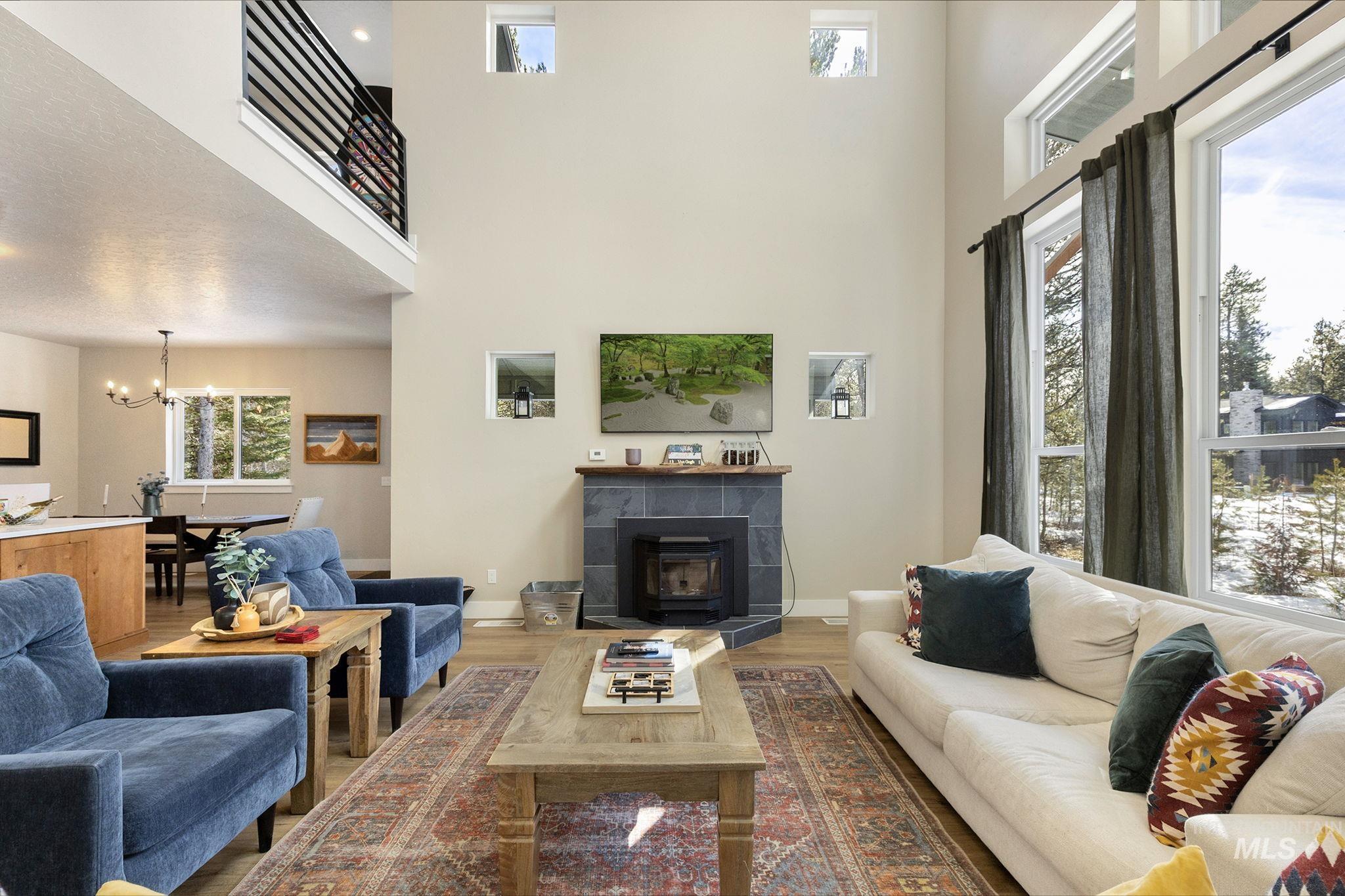 127 Jacks Loop Donnelly, ID 83615 - Photo 9 of 46 Living area featuring a fireplace, a chandelier, wood finished floors, and a high ceiling