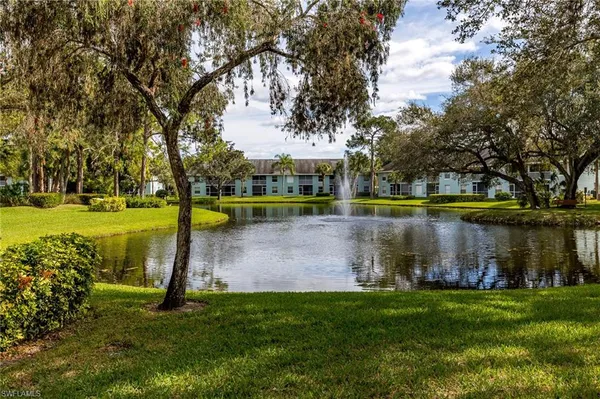 a view of a lake with a yard and large trees