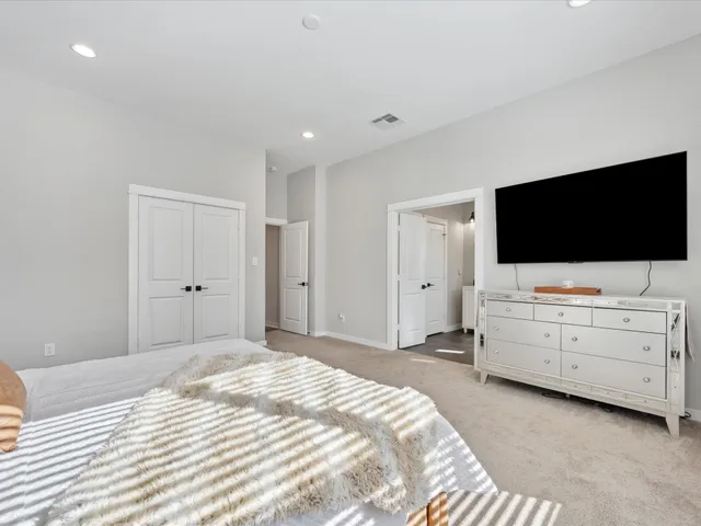 a bedroom with a bed and a flat screen tv in white room