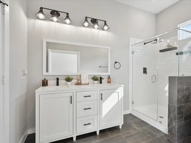 a spacious bathroom with a double vanity sink a mirror a shower and a mirror