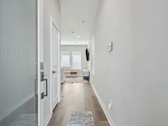 a view of a hallway with a white walls and wooden floor