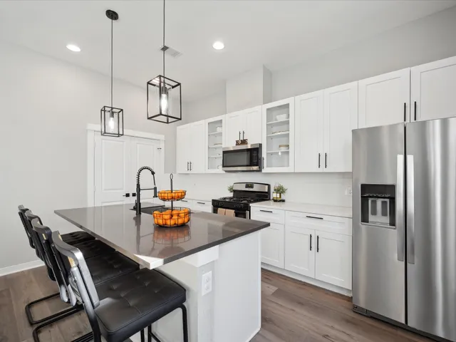 a kitchen with a refrigerator a stove a sink and chairs