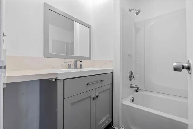a bathroom with a tub sink double vanity and mirror