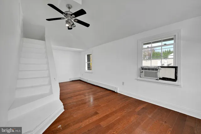 an empty room with wooden floor fan and windows