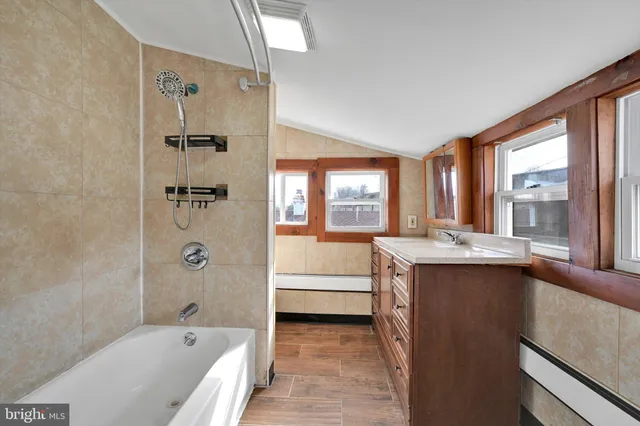 a bathroom with a granite countertop tub sink a window and a shower