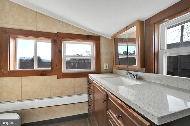 a bathroom with a granite countertop sink and a large mirror next to a window