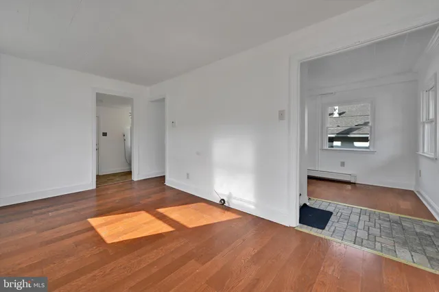 a view of empty room with wooden floor and window