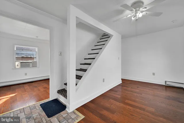 a view of an empty room with wooden floor and a ceiling fan