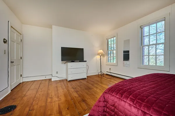 a bedroom with a bed a chair and potted plant