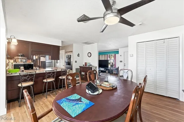 a dining room with wooden floor a chandelier fan a wooden table and chairs