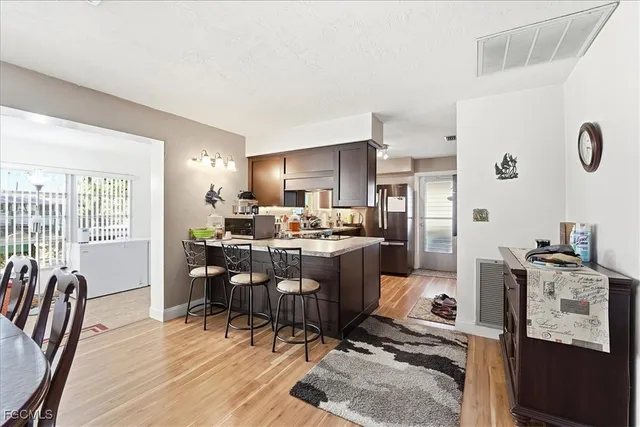 a room with stainless steel appliances kitchen island granite countertop a table chairs in it and a window