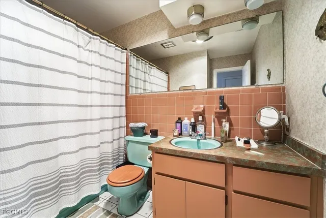 a bathroom with a granite countertop toilet sink and mirror