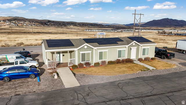 15371 Frontage Road Santaquin, UT 84655 - Photo 16 of 18 View of front of house featuring a shingled roof, solar panels, a porch, a mountain view, and a front yard