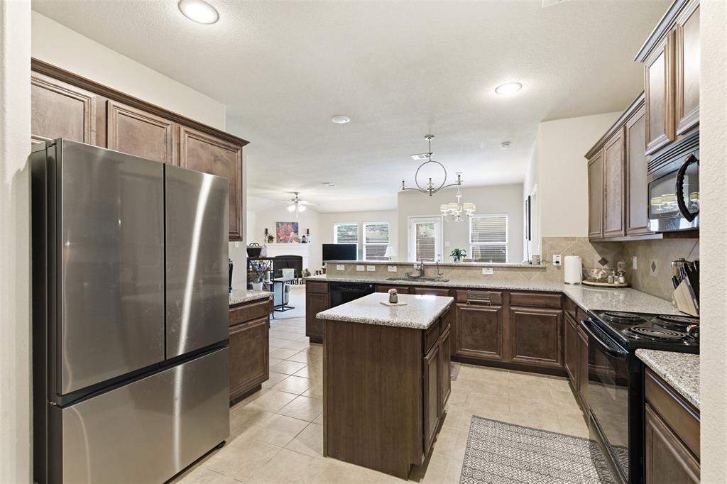 5491 Exeter Drive Prosper, TX 75078 - Photo 5 of 20 a kitchen with granite countertop a sink stove and refrigerator