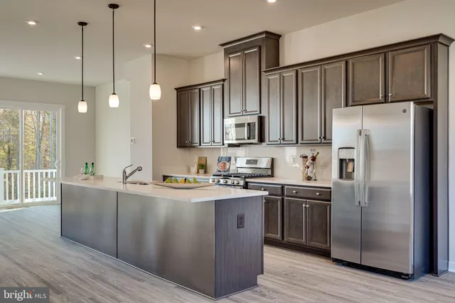 a kitchen with stainless steel appliances granite countertop a refrigerator a sink dishwasher a stove and white cabinets with wooden floor