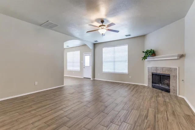 a view of an empty room with a window and wooden floor
