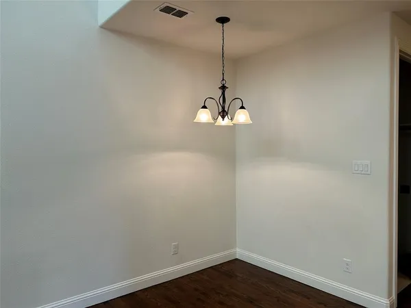 a view of a room with a chandelier fan and wooden floor