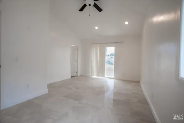 an empty room with view of ceiling fan and window